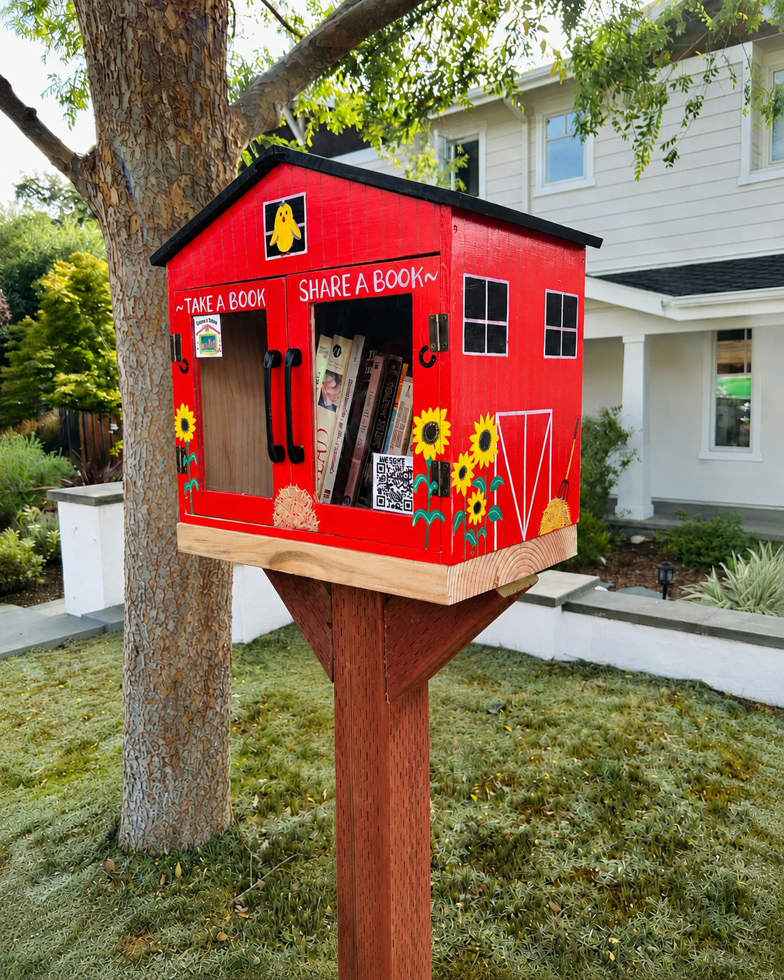 A bright red hand-painted Book Trails box with sunflowers and Take a Book, Share a Book lettering